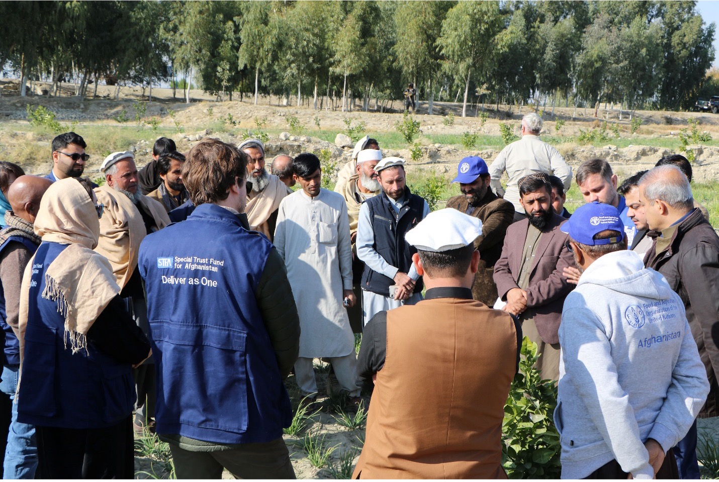 STFA representatives and a group of farmers standing in a former poppy farming field.