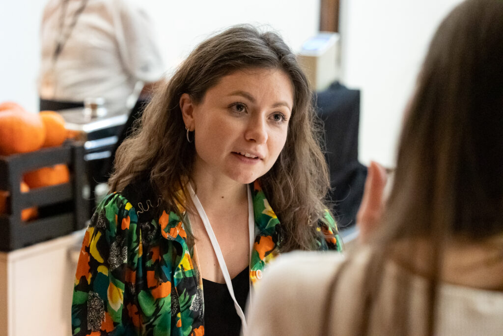 Alina Cebotari, woman with brown long hair in a colorful shirt, in a conversation with another woman, listening attentively 