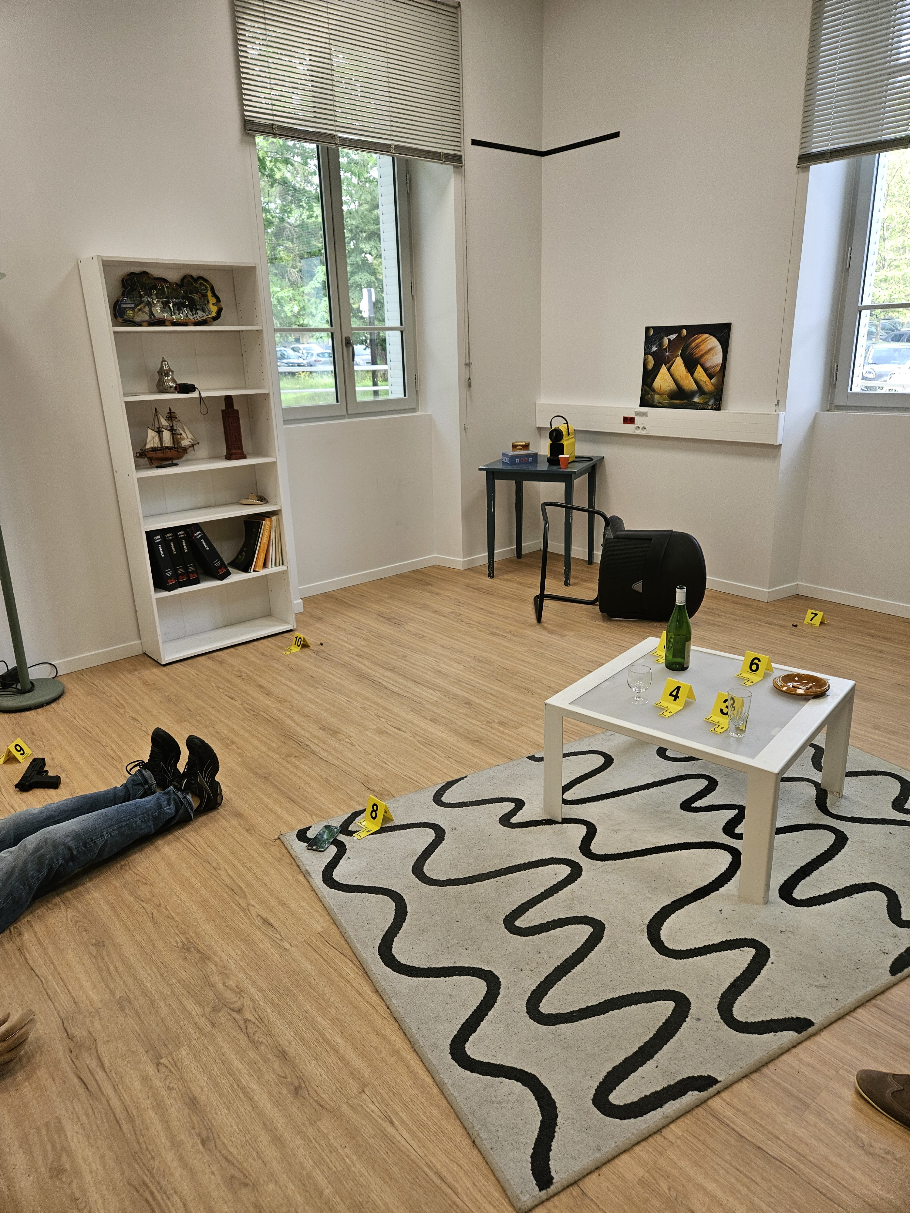 N Balkans SALW crime scene in an apartment with yellow crime scene markers, legs of a person on the bottom right, a gun next to the legs, among other markers