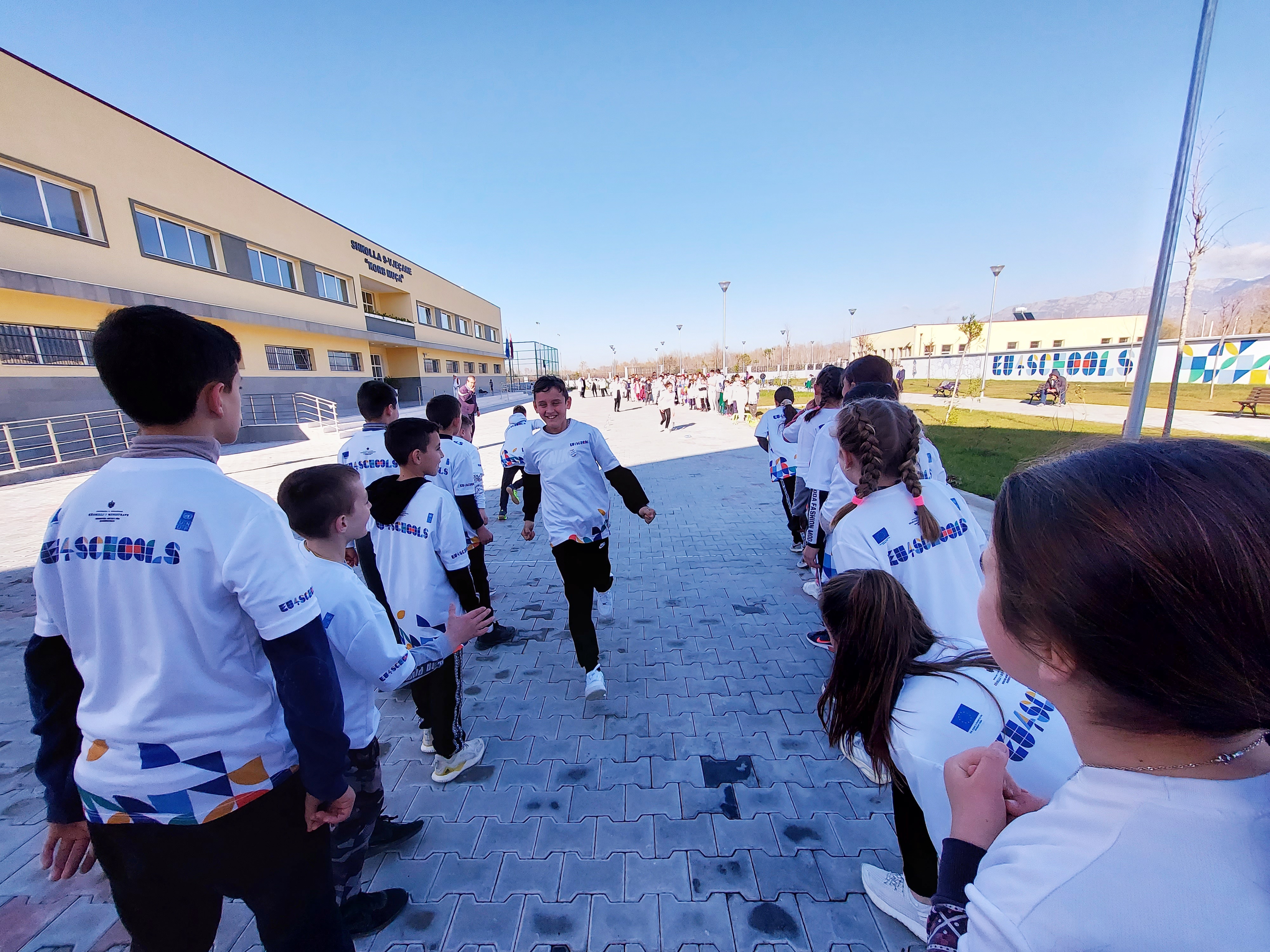 Children of Qereke in school uniforms and backpacks, giggle as they walk to their schools and kindergartens 