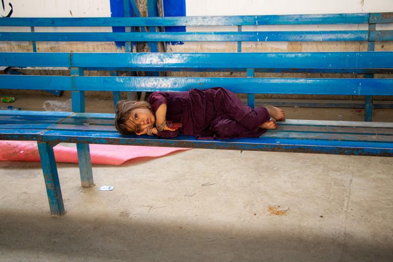 A young girl rests at Torkham border as she returns with her family
