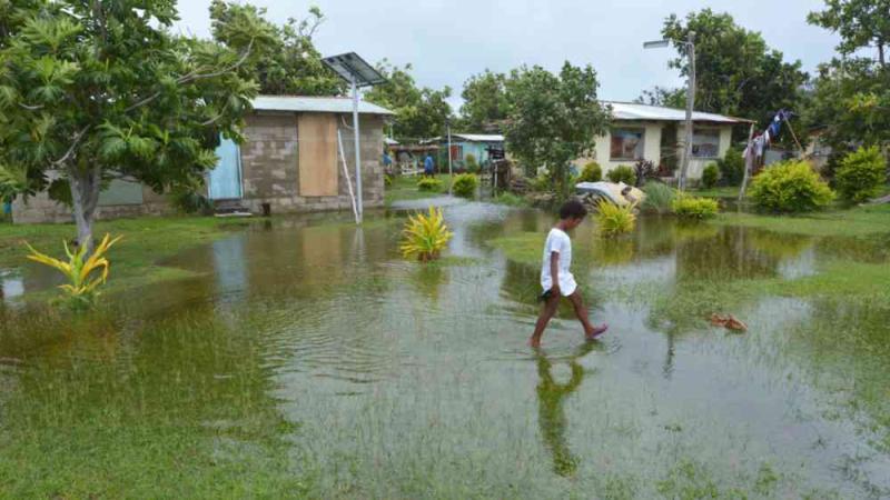 Indigenous Fijian girl walking on flooded land in Fiji.